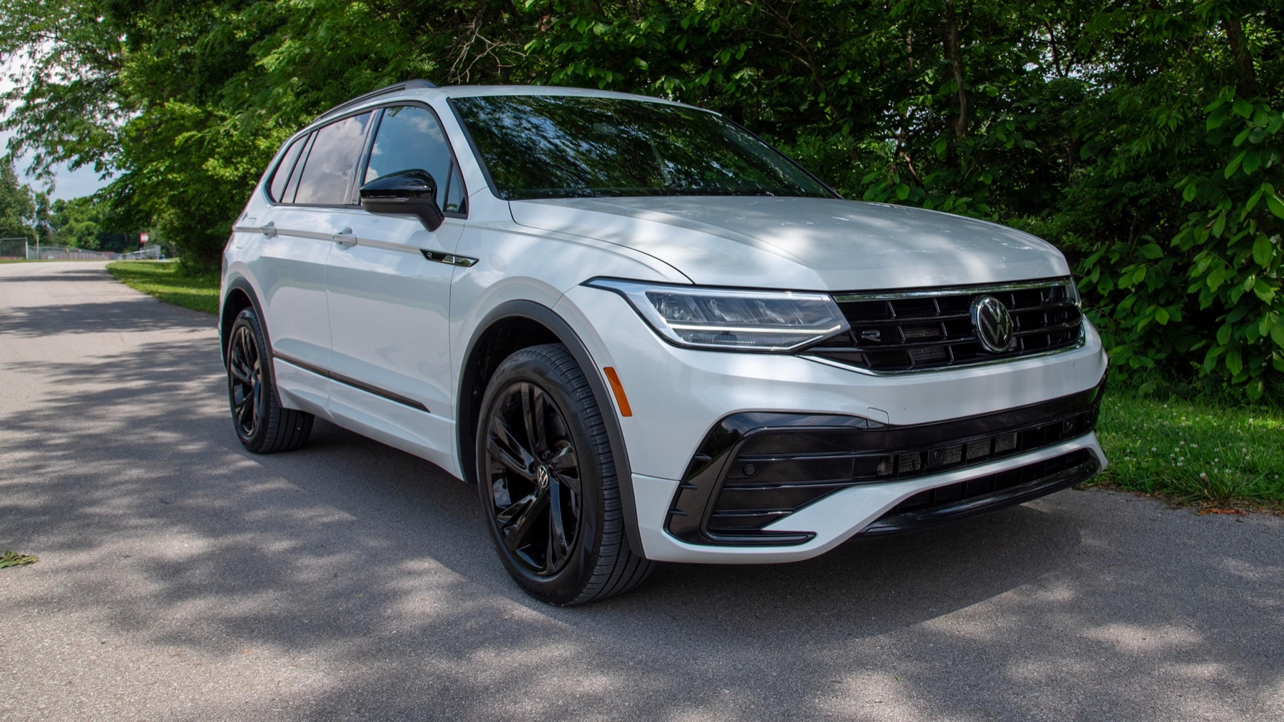 White Volkswagen Tiguan parked on a tree-lined road